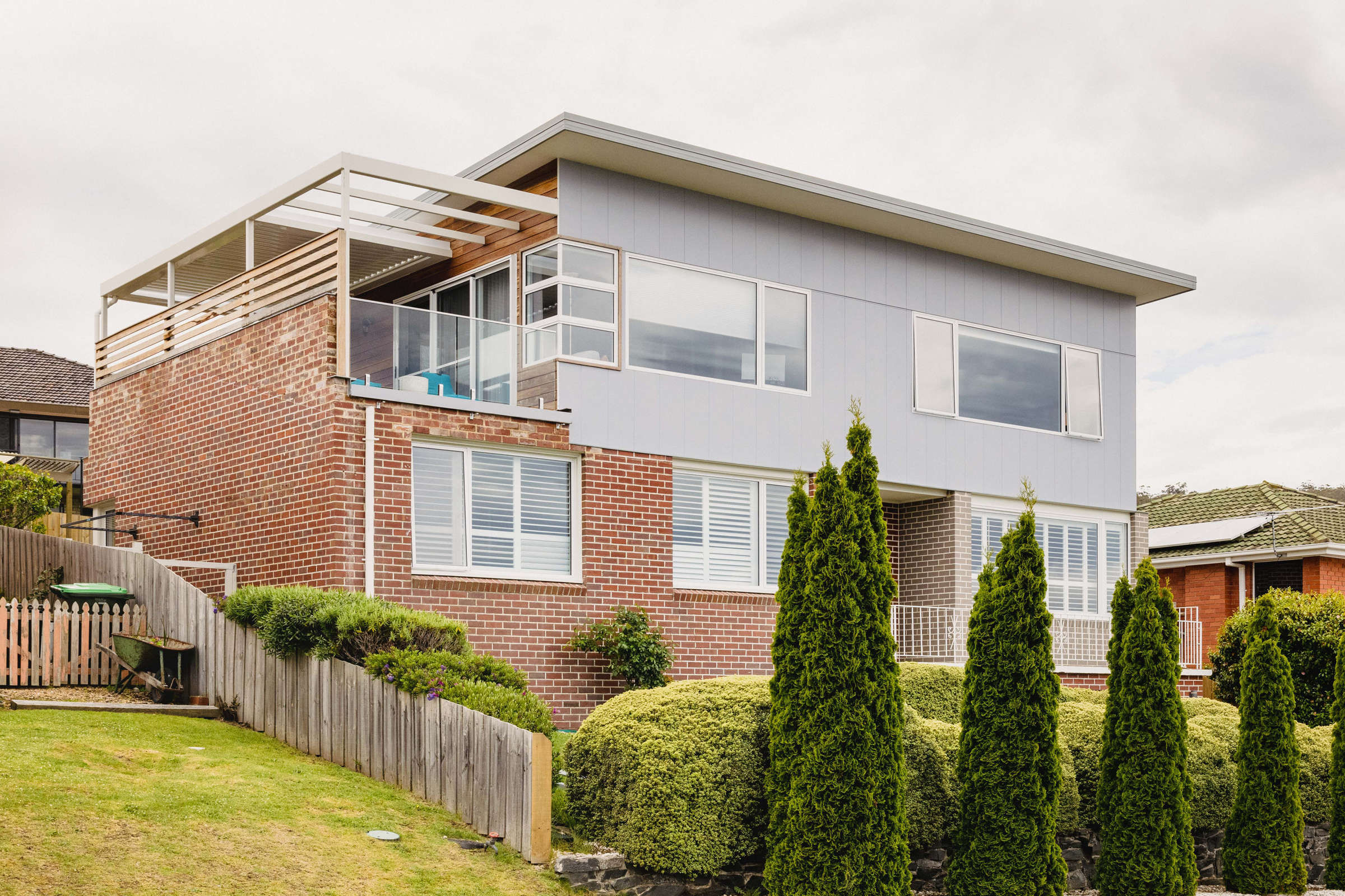 This Howrah home renovation added a second storey to a double brick 1960s house as a lifestyle renovation. It features steel framework over an external deck, motorised louvre system, sauna, ensuite bathroom, glass balustrade and a beautiful view. Photo: Jordan Davis.