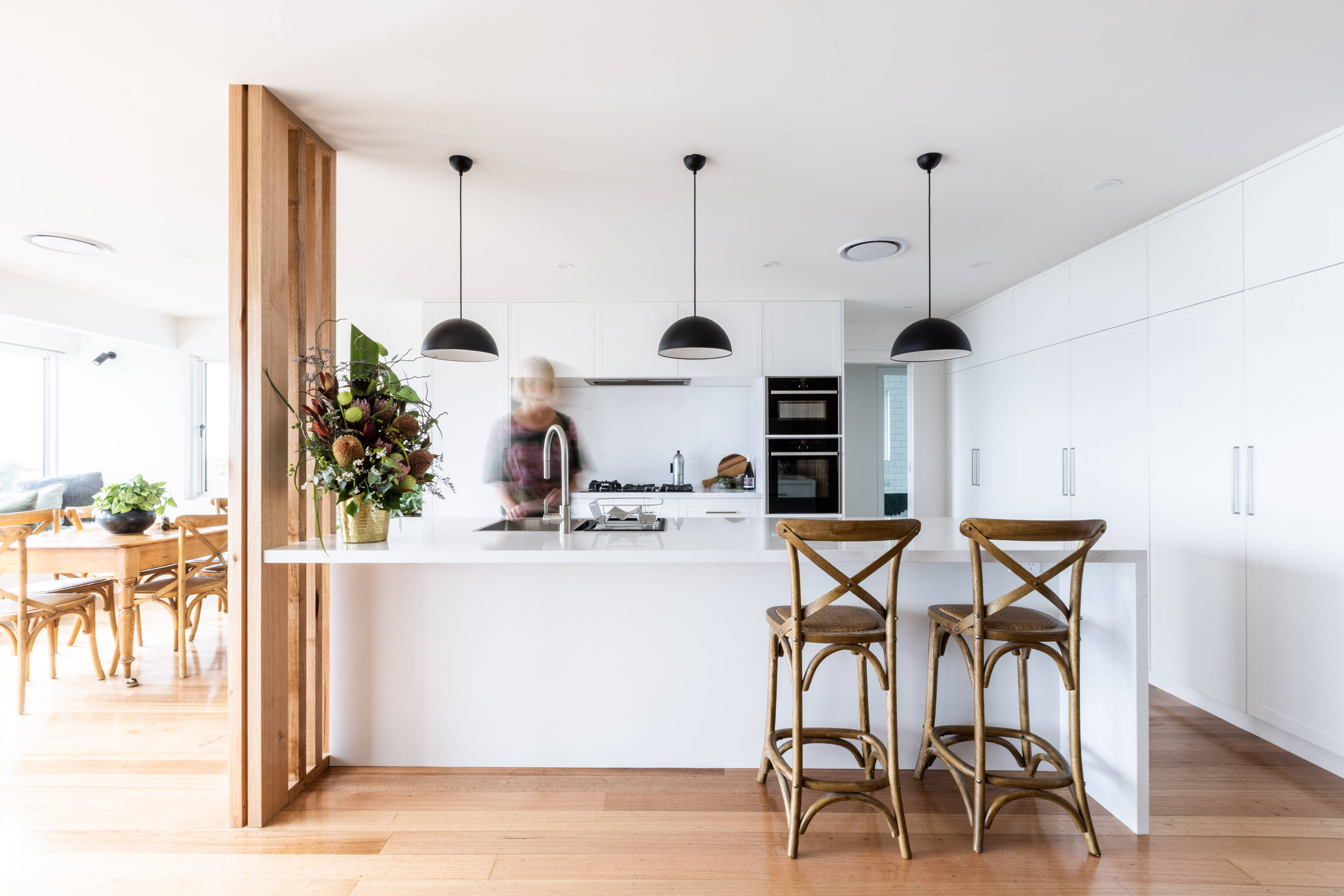 This light and bright, contemporary kitchen renovation has transformed this 1970s house and features solid stone benchtops, pendant lighting, contemporary lighting, brushed chrome tapware and an in bench sink. Photo: Jordan Davis.