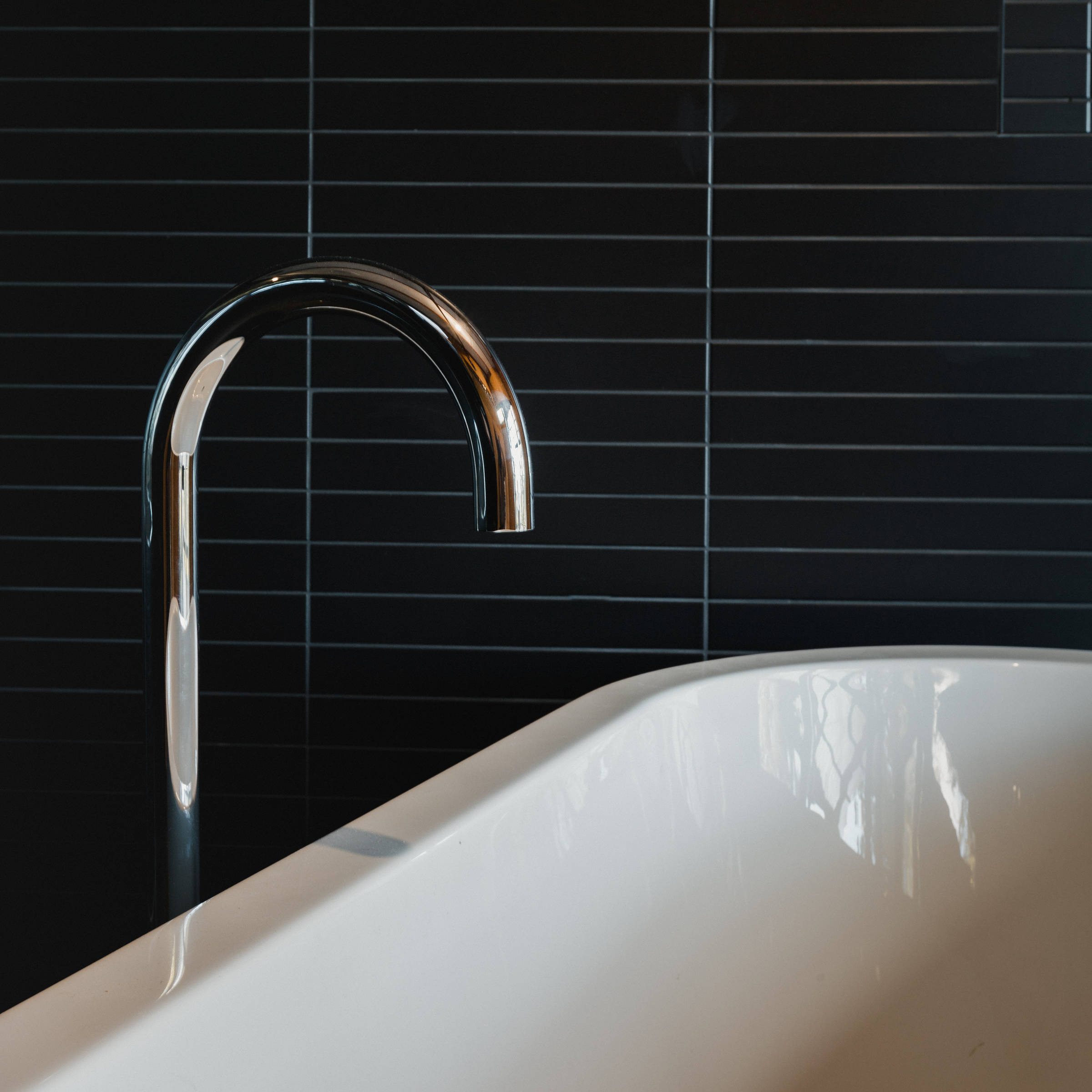A Japanese inspired bathroom renovation with a freestanding bath, highlighted by black mosaic tiles and chrome tapware. Photo: Jordan Davis.