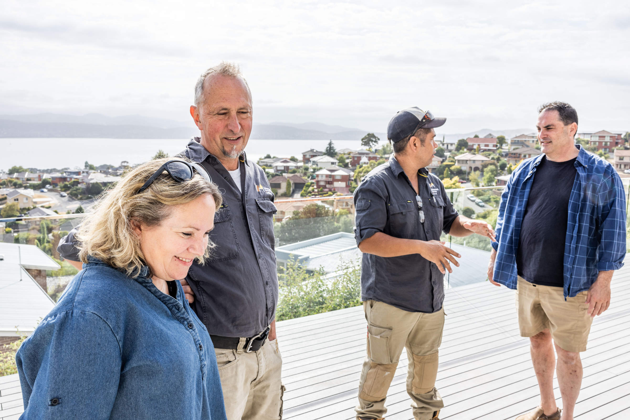 The Enhanced Homes team consulting with our clients about the renovation of their 1970s home, standing on their new deck with view of the River Derwent. Photo: Jordan Davis.