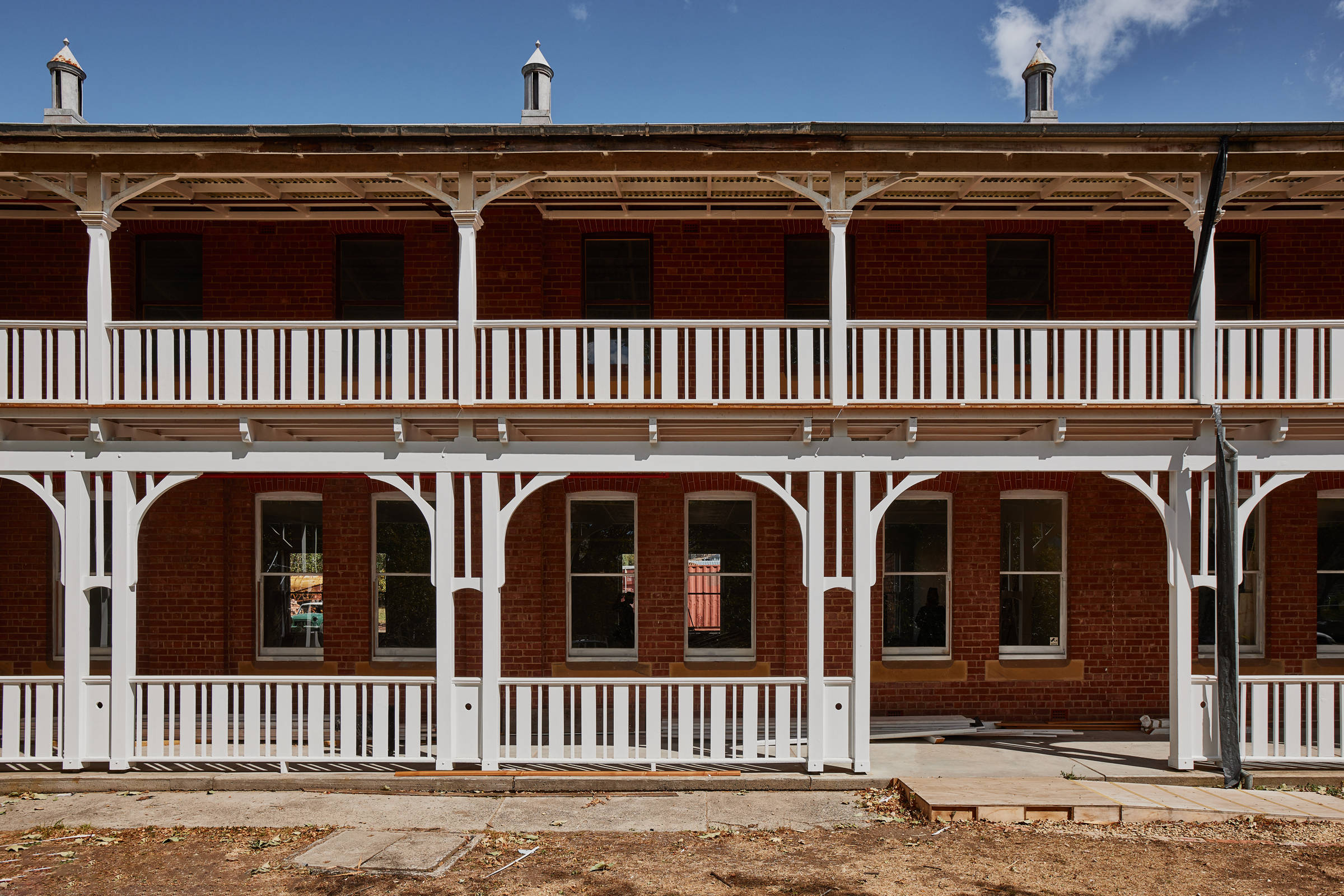 Front view of a double storey heritage building and a freshly painted white verandah with decorative supports and balustrades, and two heritage roof vents. Credit: Samuel Shelley.